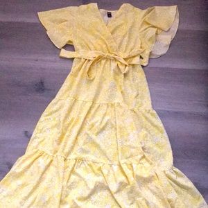 This is a light yellow maxi dress with white flowers and a tie bow